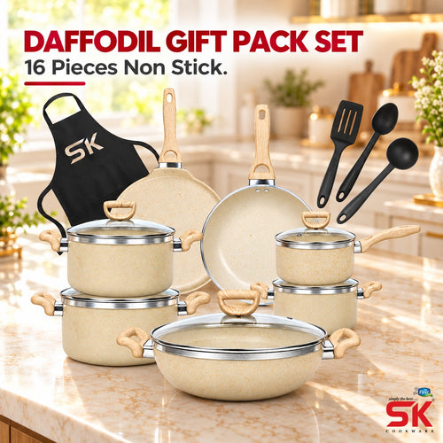 A 16-piece non-stick cookware set displayed on a kitchen countertop with a blurred kitchen background. The set includes beige stoneware pots and pans with light wood handles and lids, black non-stick utensils, and a black apron-style pot holder with a white SK logo.