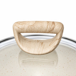 Close-up of a light beige wood-textured pot lid handle resting on a speckled cream-colored glass lid with a silver metal rim, against a white background.