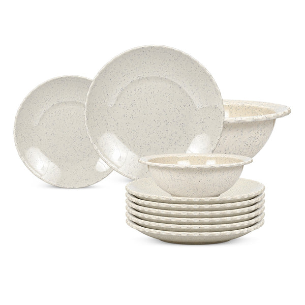 A set of speckled ceramic dinnerware in a warm off-white/cream color, including plates, bowls, and stacked saucers, photographed on a clean white background.
