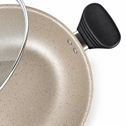 Close-up of a speckled beige non-stick pan with a black handle and a glass lid partially visible, set against a clean white background.